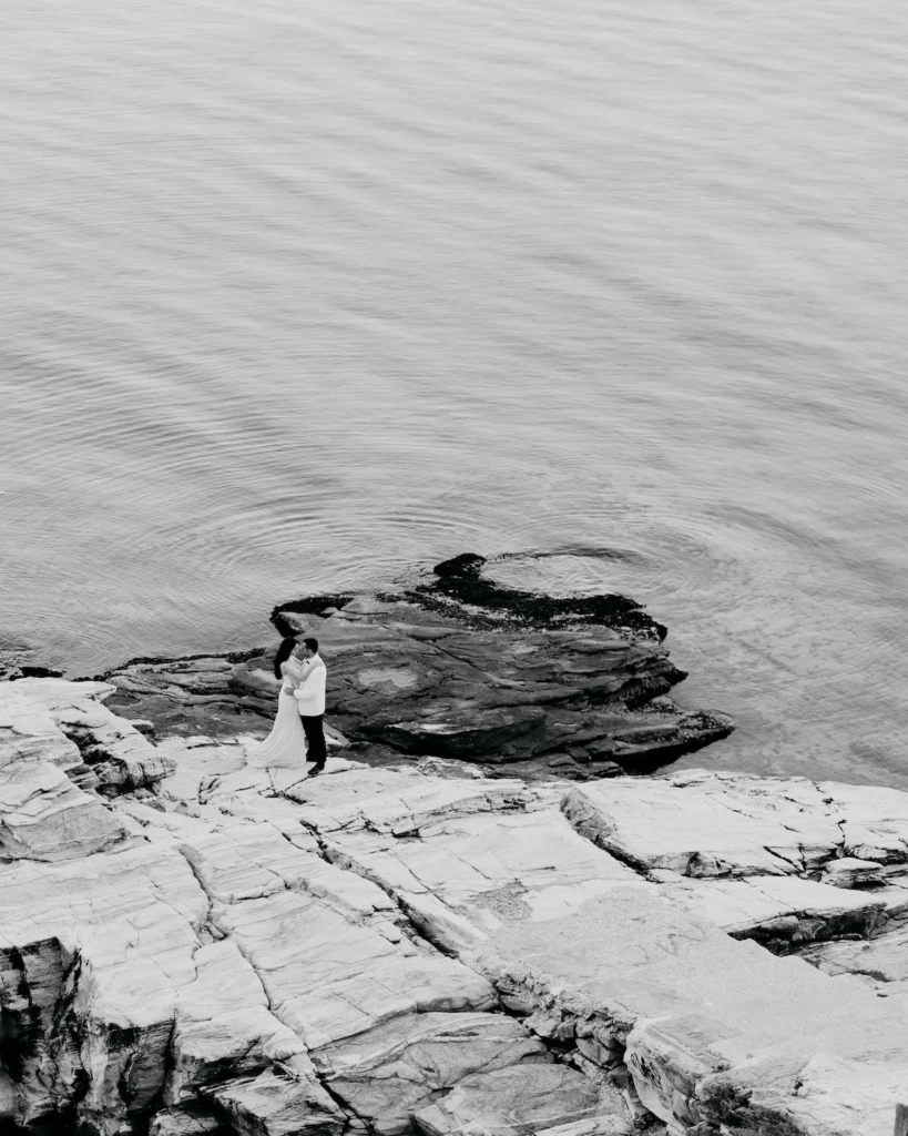 Anastasia and Aggelos standing on dramatic white marble rocks above the sea