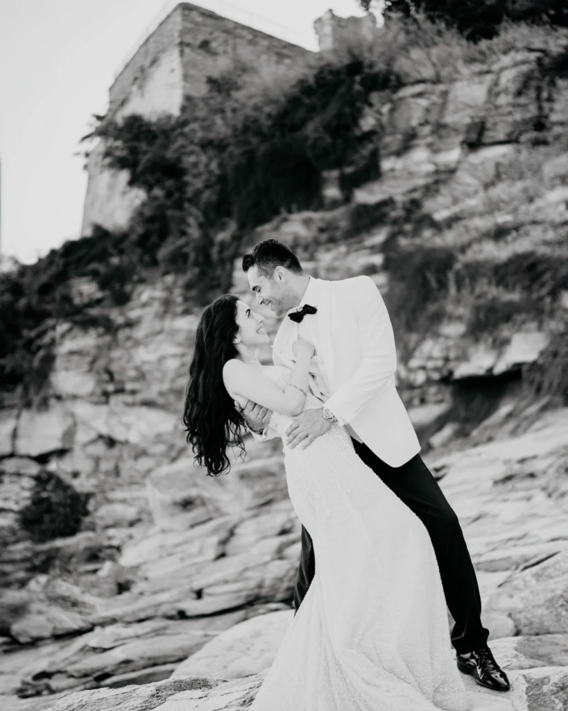 Anastasia and Aggelos standing on white marble rocks above the calm sea