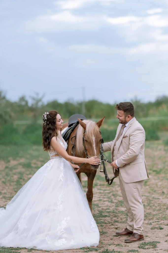 Elena and Vasilis sharing a quiet moment beside a horse in the countryside