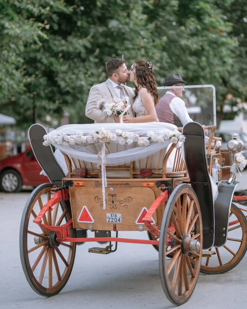 Elena and Vasilis riding a horse-drawn carriage through the countryside on their wedding day