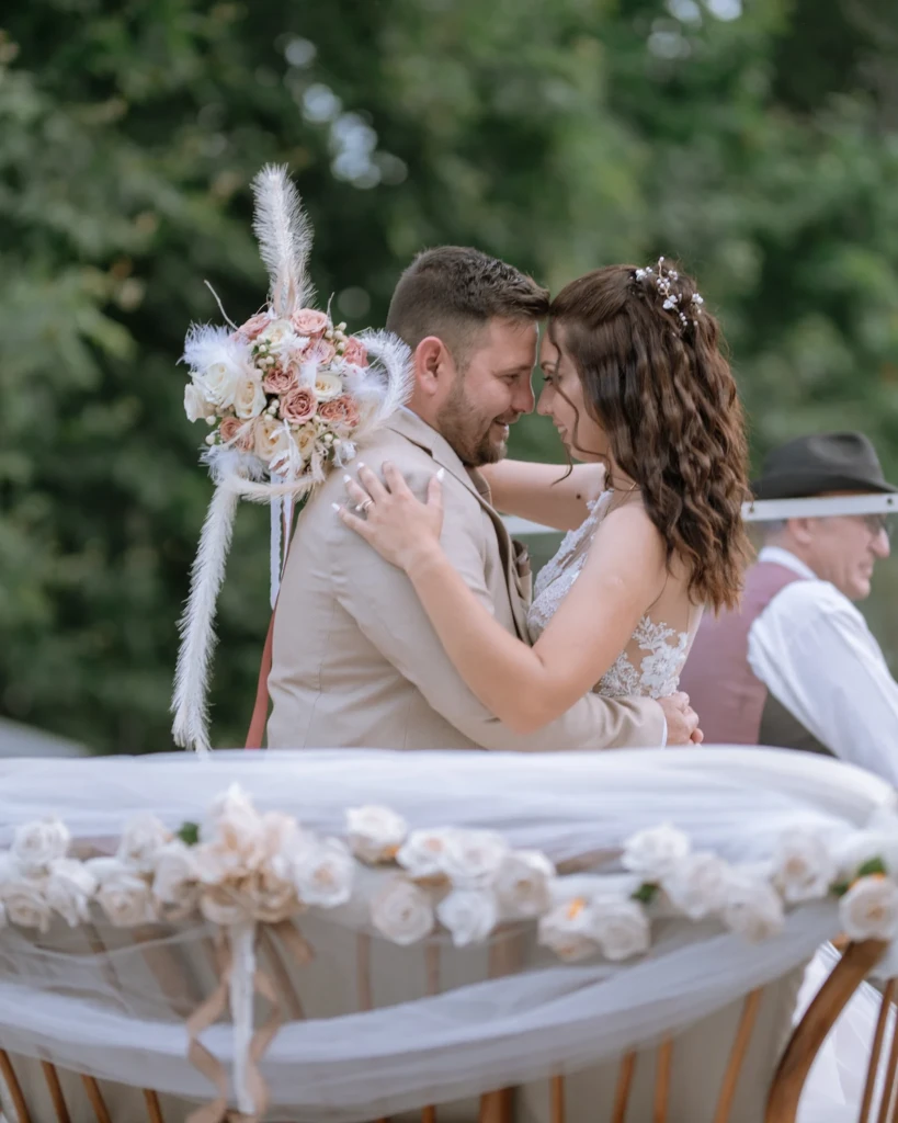 Elena and Vasilis embracing at their outdoor wedding ceremony, the bride holding her bouquet