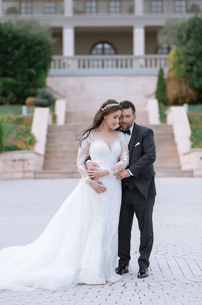 Loukiani and Giorgos embracing on a staircase by tall arched windows